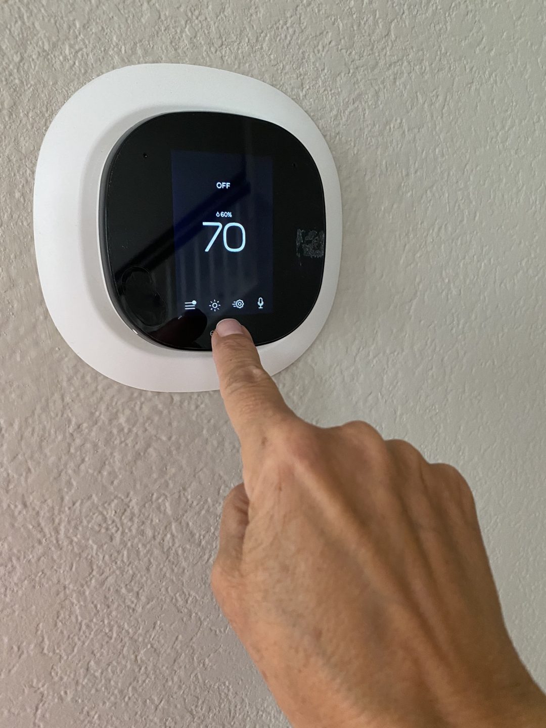 A homeowner and woman adjusts the settings and temperature on her ecobee smart thermostat